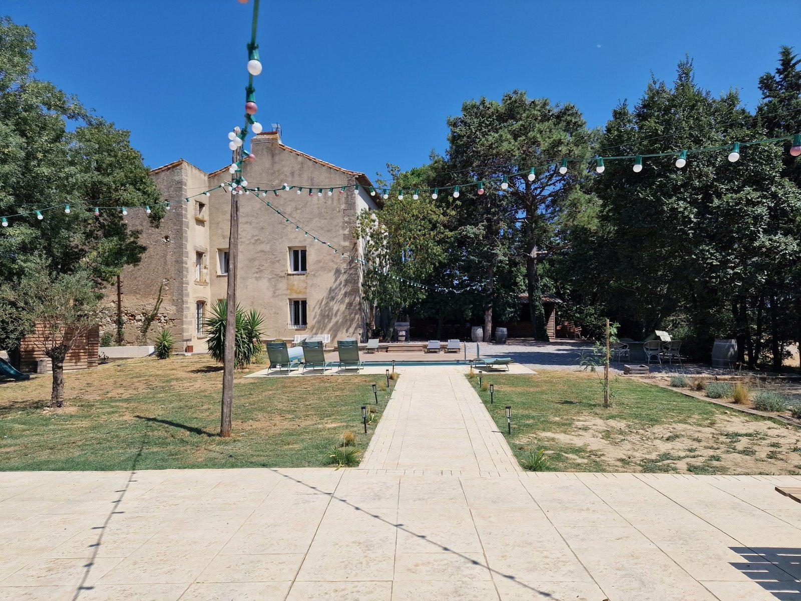 Jardin arboré et chemin menant à la piscine d’un gîte de groupe à Narbonne