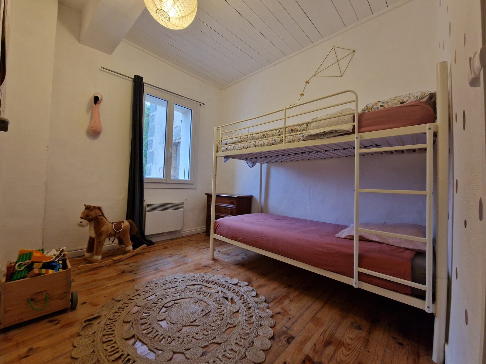 Chambre enfants du gîte à Narbonne avec lits superposés, parquet en bois et espace de jeux.