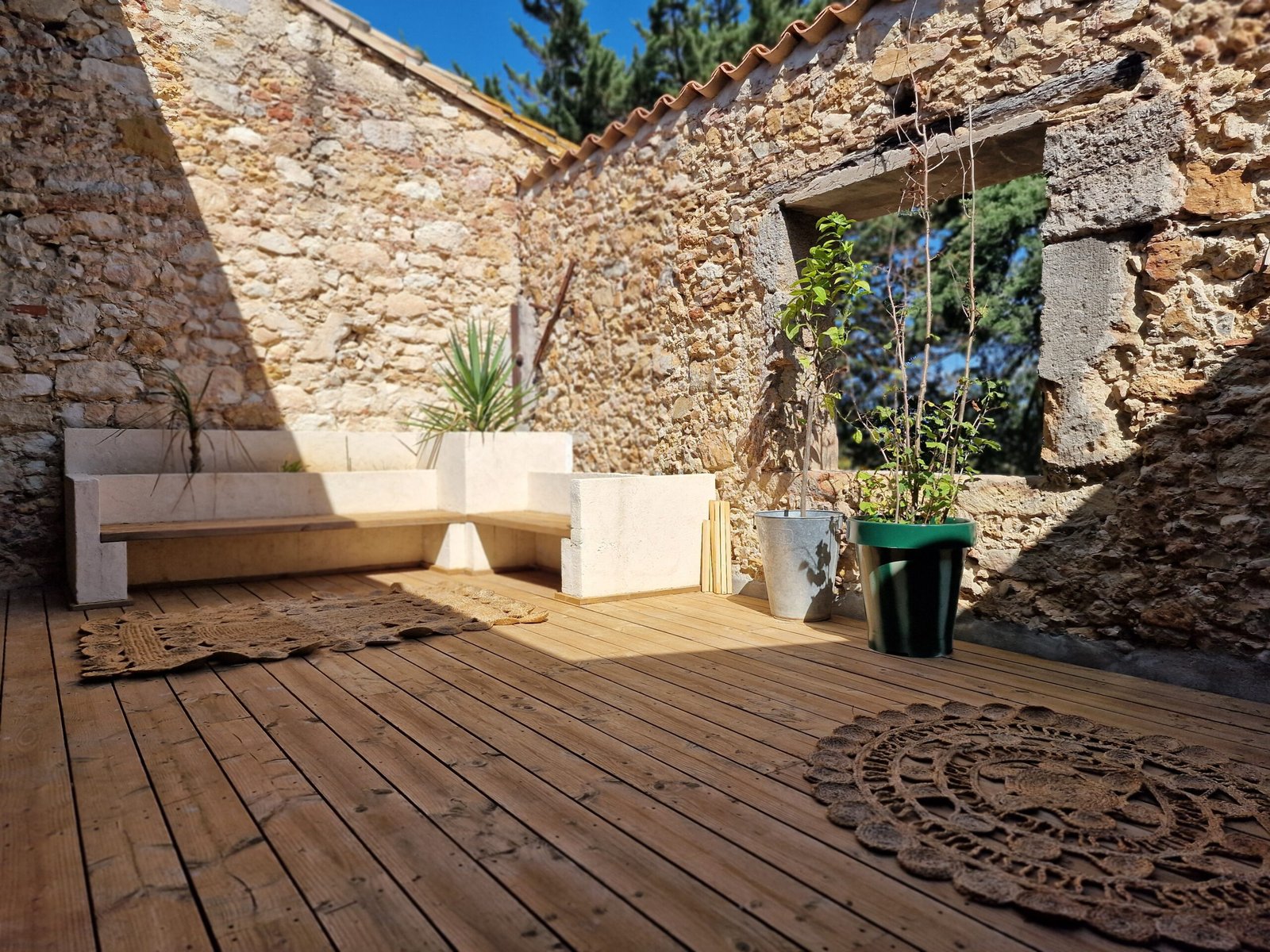 Terrasse en pierre et bois du gîte à Narbonne avec coin détente, plantes et ouverture sur la végétation.